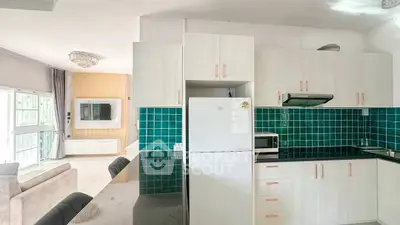 Modern kitchen with green tile backsplash and sleek appliances in open layout
