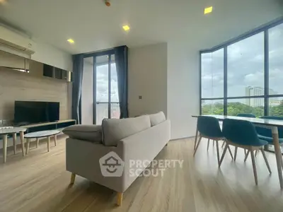 Spacious modern living room with large windows and stylish furniture offering a serene view.