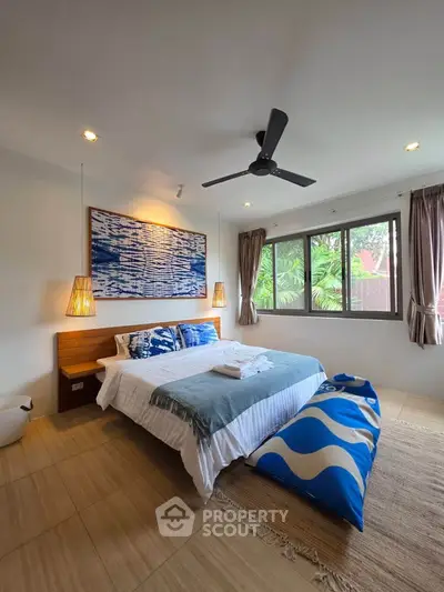 Spacious bedroom with modern decor and large windows offering lush garden views.