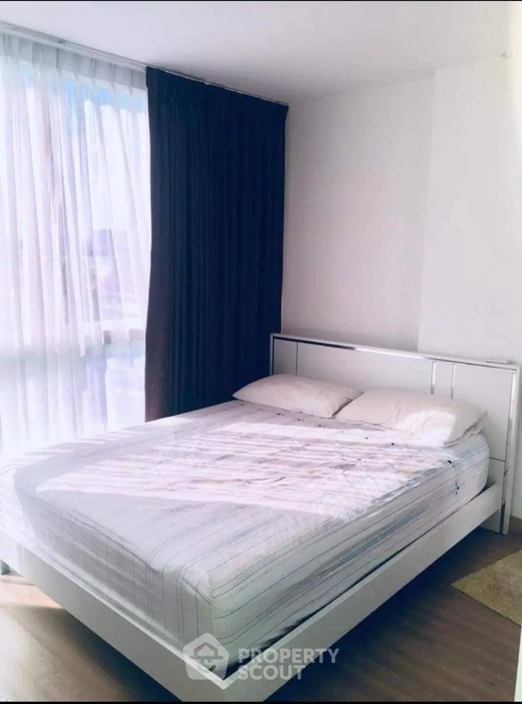 Bright and cozy bedroom with large window and modern bed frame, perfect for relaxation.