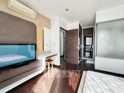 Modern bedroom with sleek design and natural light, featuring a built-in TV and stylish furniture.