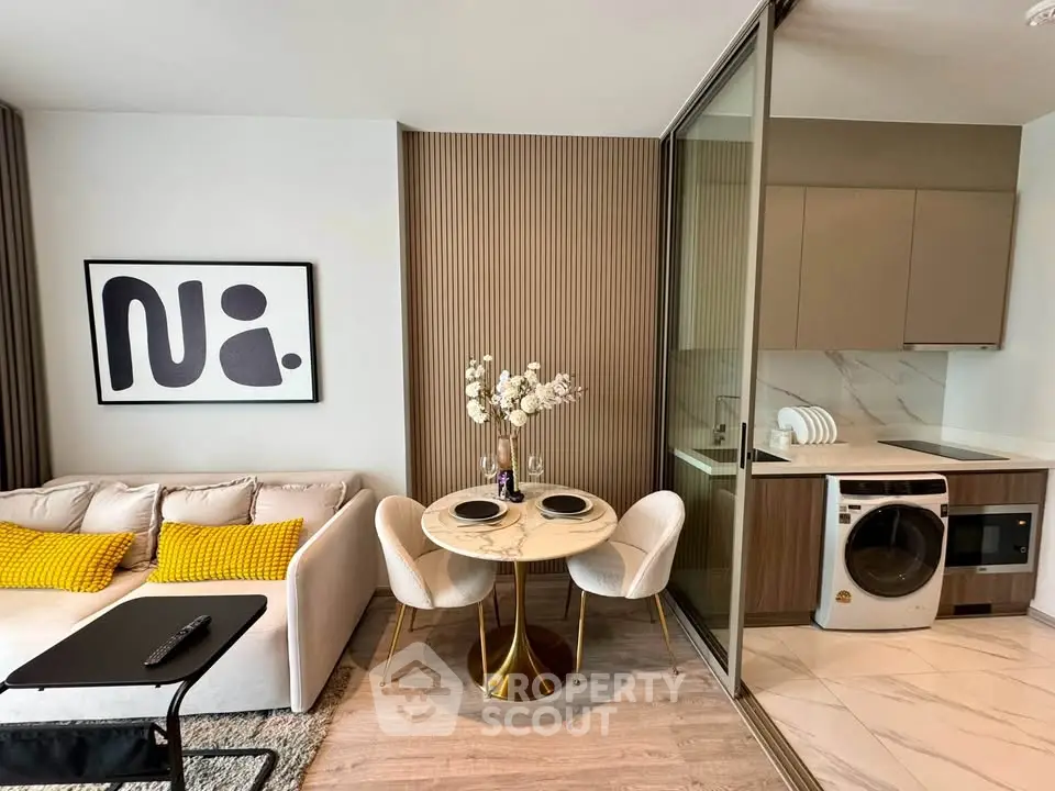 Modern living room with stylish decor and compact kitchen featuring a washing machine.