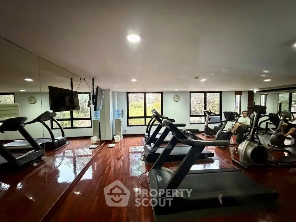 Spacious gym with modern equipment and large windows offering scenic views.