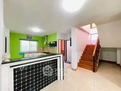 Modern kitchen with vibrant green walls and staircase in open layout home