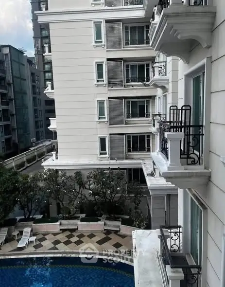 Elegant residential building with pool view and balconies in urban setting.