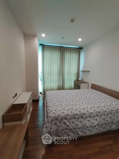 Modern bedroom with wooden flooring and large window with curtains in a cozy apartment.