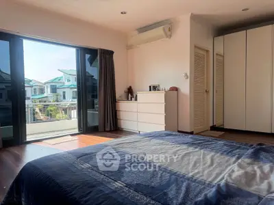 Spacious bedroom with balcony view in modern home, featuring large windows and ample natural light.