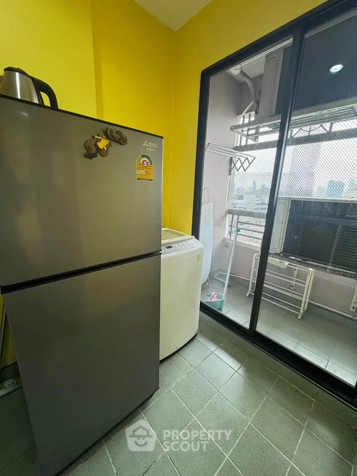 Modern laundry area with washing machine and balcony access in urban apartment.