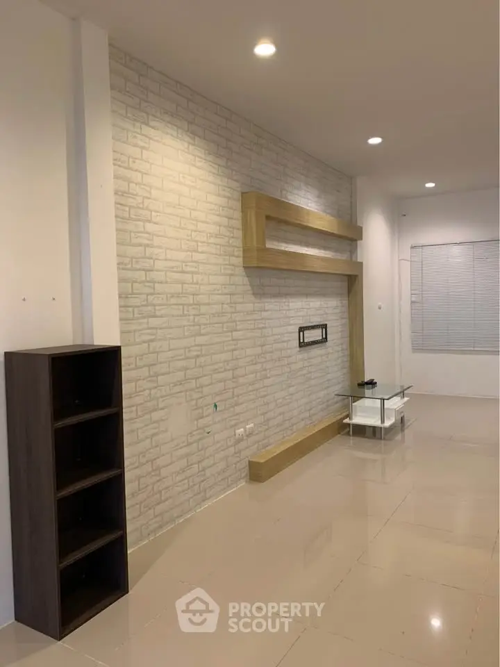 Modern living room with stylish brick accent wall and sleek shelving unit.