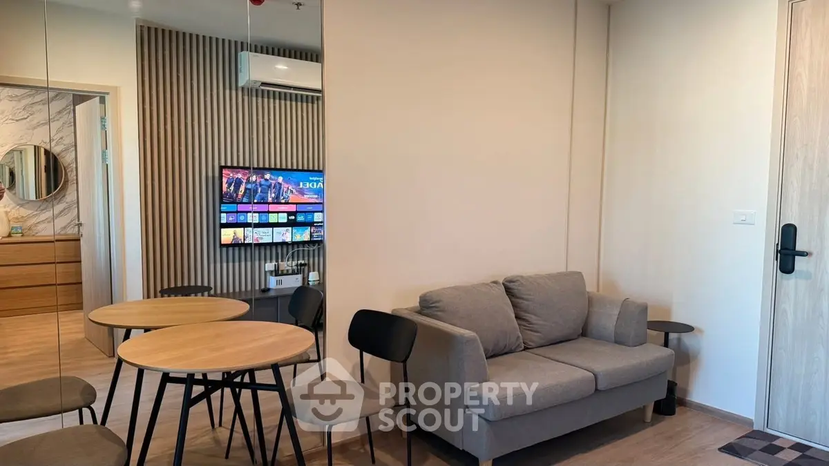 Modern living room with cozy sofa, round table, and wall-mounted TV in stylish apartment.