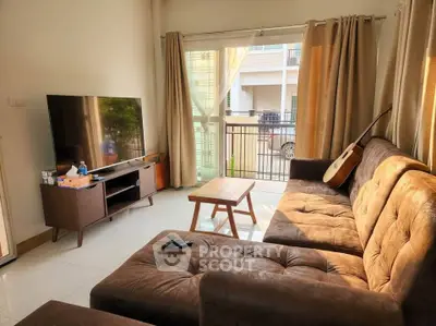 Cozy living room with plush sectional sofa, large TV, and natural light from balcony.