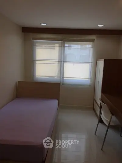 Cozy bedroom with natural light, featuring a single bed and study desk, perfect for a student or professional.