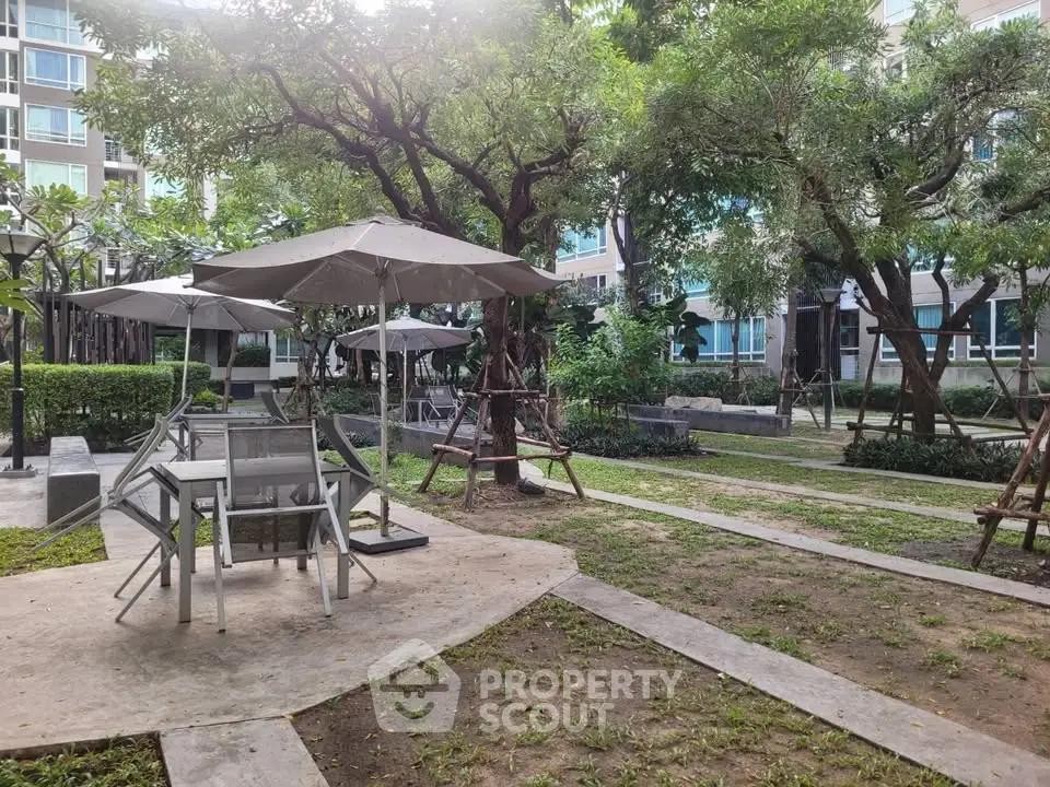 Charming garden area with seating and umbrellas in modern residential complex.