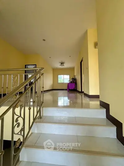 Spacious hallway with elegant staircase and bright yellow walls