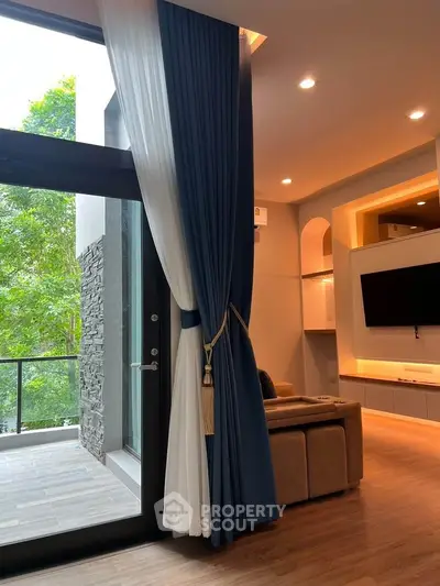 Luxurious living room with floor-to-ceiling windows and elegant blue curtains overlooking greenery.