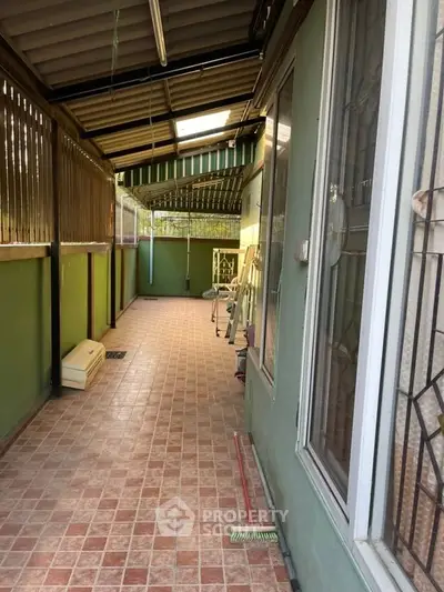 Charming covered balcony with tiled flooring and green walls, perfect for relaxation or entertaining guests.