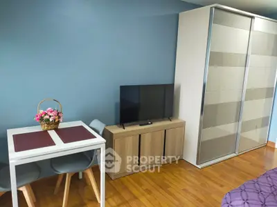 Modern living room with sleek TV stand, stylish dining set, and spacious wardrobe in a cozy apartment.