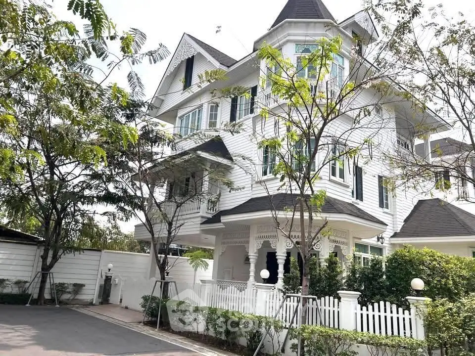 Charming Victorian-style house with lush garden and white picket fence