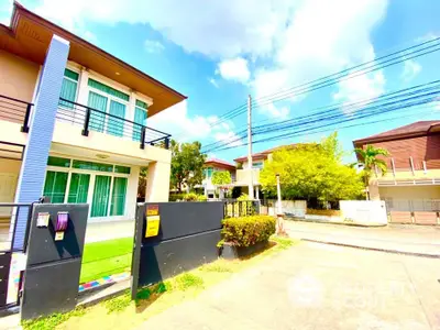 Modern two-story house with balcony and lush greenery in a serene neighborhood.