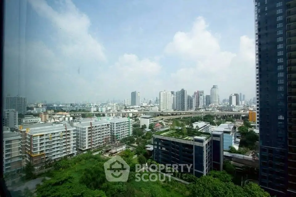 Stunning cityscape view from high-rise apartment with lush greenery and modern buildings.