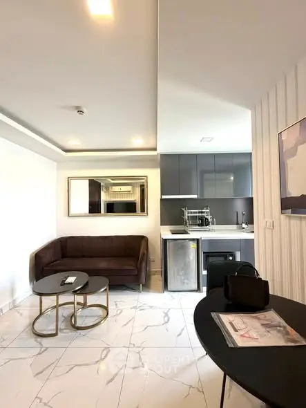 Modern living room with sleek kitchen, marble flooring, and stylish furniture.