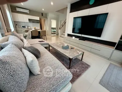 Spacious modern living room with stylish decor and large TV, perfect for relaxation and entertainment.
