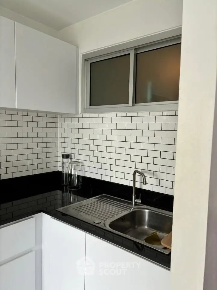 Modern kitchen with sleek black countertops and white subway tile backsplash.