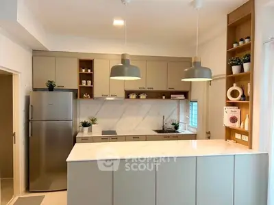 Modern kitchen with sleek cabinetry, stainless steel fridge, and stylish pendant lighting.