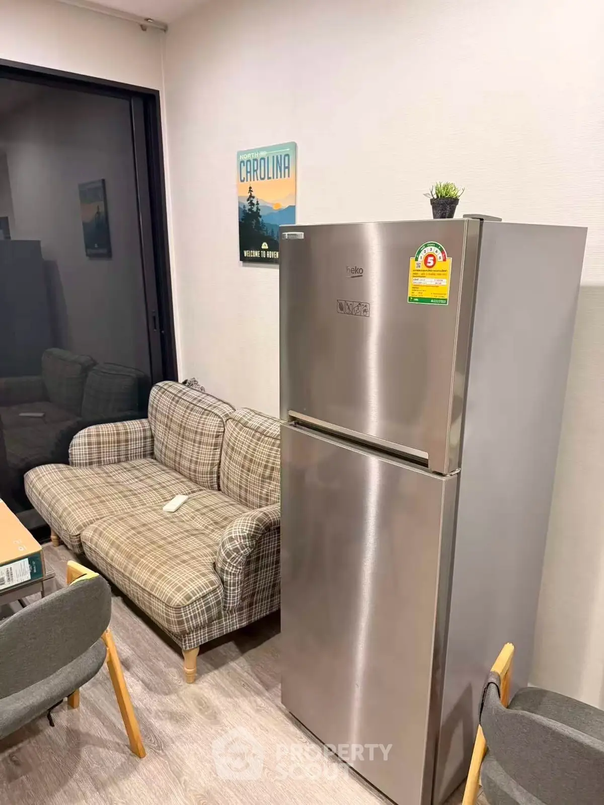 Cozy living room with plaid sofa and modern stainless steel fridge, perfect for urban living.