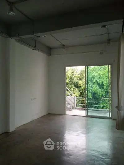 Spacious room with large window and lush greenery view, perfect for creative living.