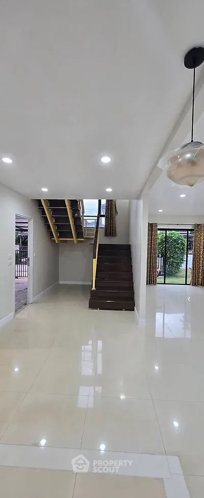 Spacious modern living room with elegant staircase and large windows