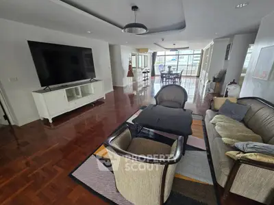 Spacious living room with elegant furniture and large TV, featuring polished wooden floors and ample natural light.