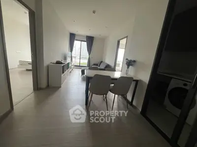 Modern apartment interior with open living and dining area, featuring stylish furniture and large windows.