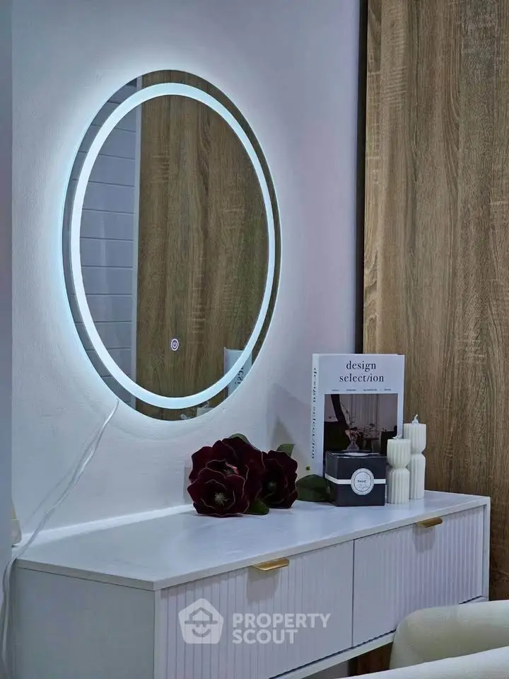 Modern bedroom with stylish round mirror and elegant decor on white dresser.