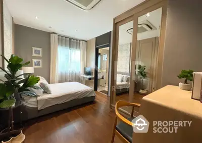 Elegant bedroom with hardwood floors, modern furnishings, and a connecting ensuite bathroom, showcasing a sophisticated urban living space.