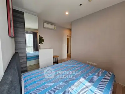 Modern bedroom with striped bedding and sleek furniture in a stylish apartment.