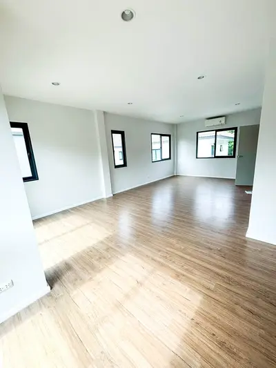 Spacious empty living room with wooden flooring and large windows for natural light.