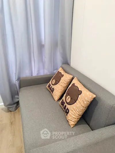 Cozy living room with gray sofa and cute bear-themed cushions.