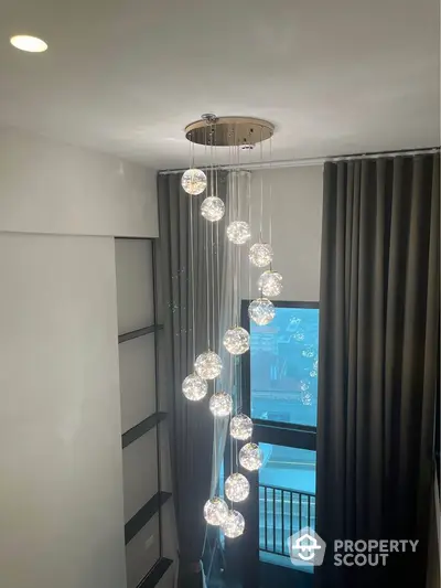 Elegant modern chandelier in stylish interior with large window and curtains