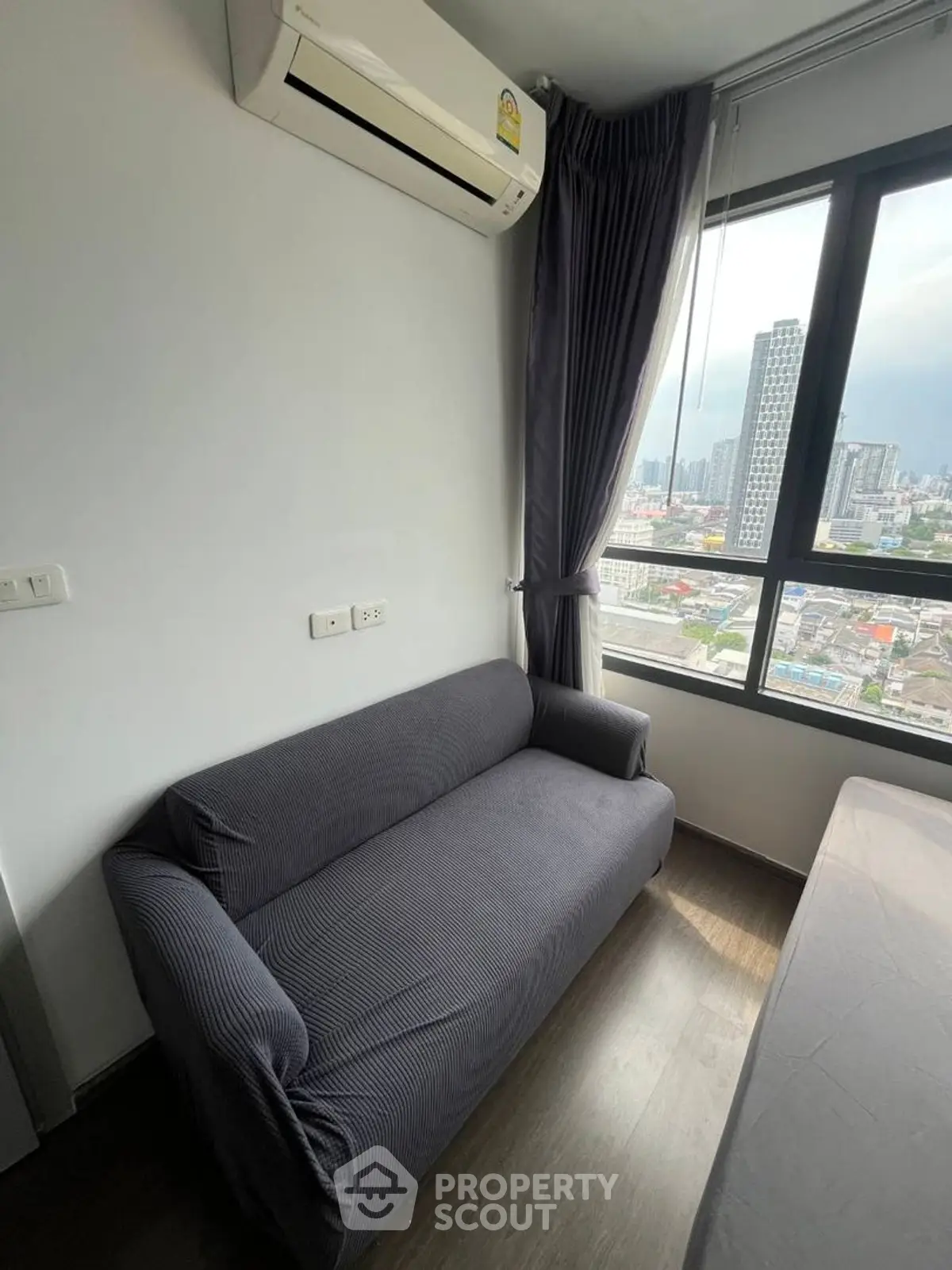 Modern apartment with city view, featuring a cozy sofa and air conditioning, perfect for urban living.