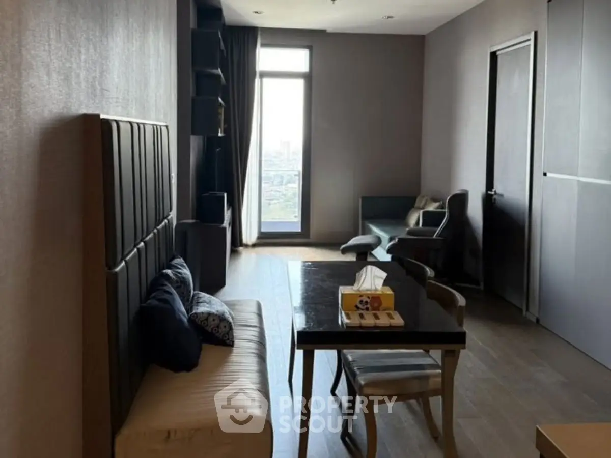 Modern living room with sleek furniture and large window offering city view.