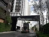 Modern residential building entrance with lush greenery and sleek architecture.