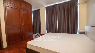 Spacious bedroom with large wooden wardrobe and elegant curtains