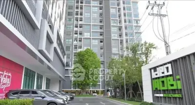 Modern high-rise condominium with parking and lush greenery in urban setting.