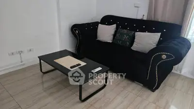 Modern living room with elegant black sofa and sleek coffee table in cozy apartment.