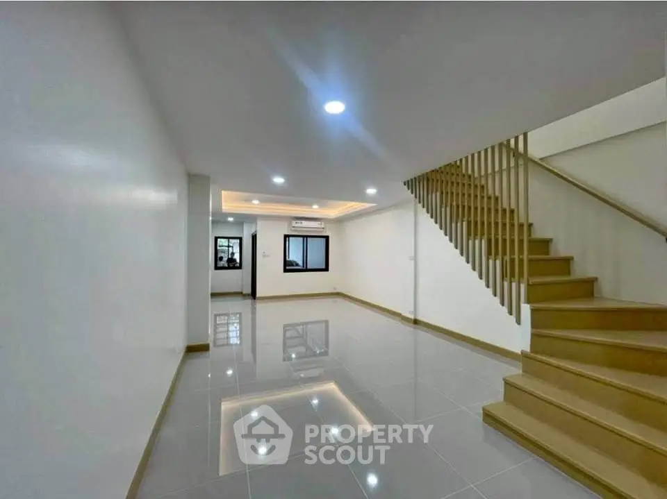 Spacious modern living room with sleek staircase and recessed lighting.