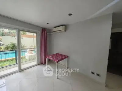 Bright room with pool view and air conditioning, featuring pink curtains and tiled floor.
