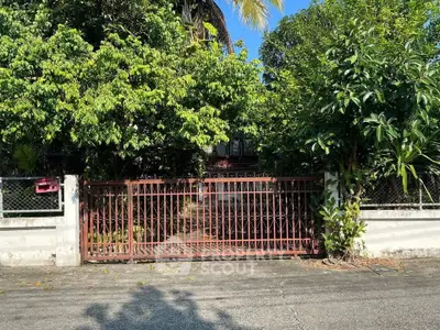 Charming gated entrance surrounded by lush greenery, offering privacy and tranquility in a serene neighborhood.