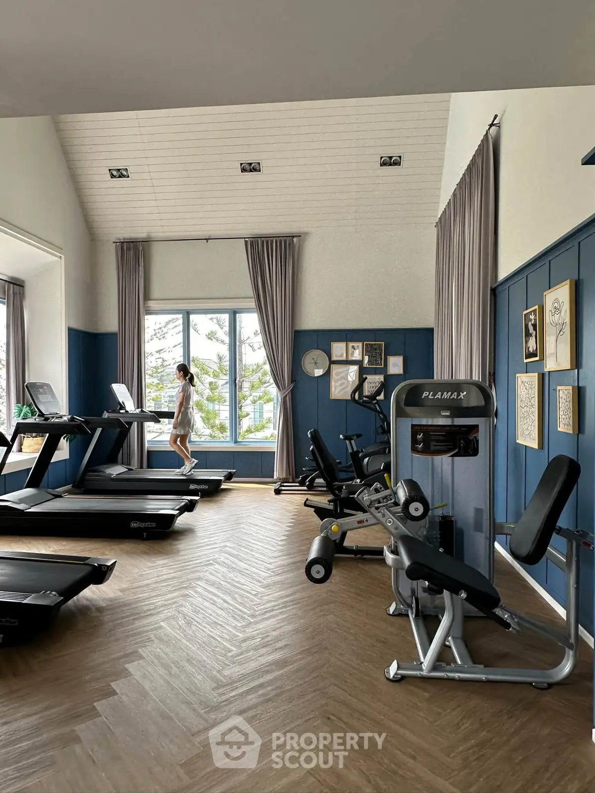 Spacious gym with modern equipment and large windows in luxury real estate property.