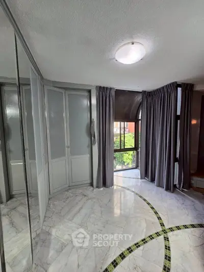 Elegant bedroom with marble flooring and large windows offering natural light and garden view.